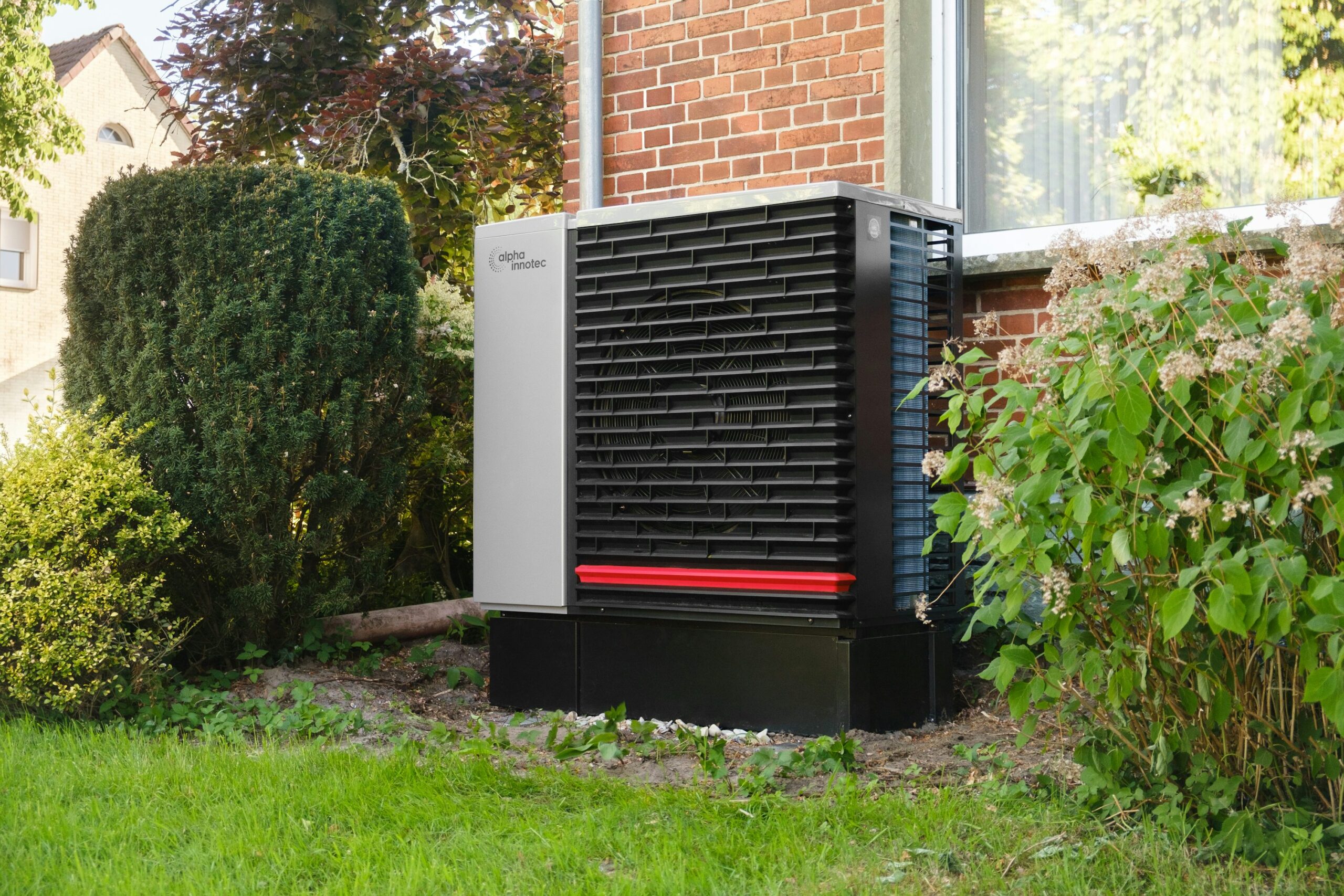 Voorbeeld van buitenunit van een warmtepomp naast een bakstenen woning